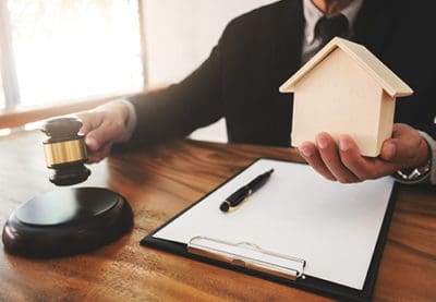 An attorney house model and gavel on a desk, symbolizing the complexities of foreclosure issues