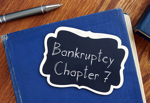 Bankruptcy Chapter 7 written on a chalkboard sign placed on a blue book