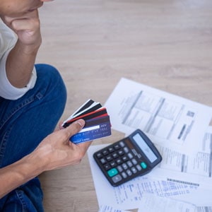 Individual reviewing credit cards and bills with a calculator, symbolizing debt settlement