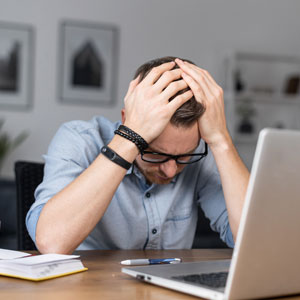 A man at a desk, head in hands, reflecting on the common challenges and scenarios of bankruptcy