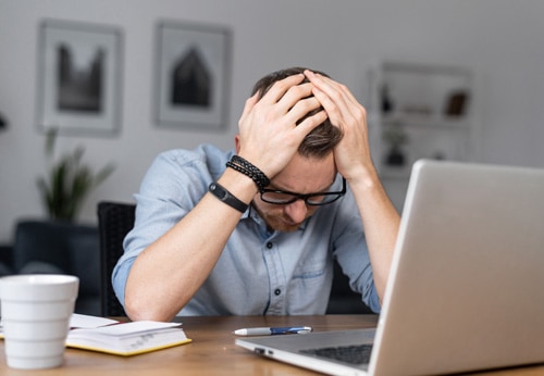 A man at a desk, head in hands, reflecting on the common challenges and scenarios of bankruptcy