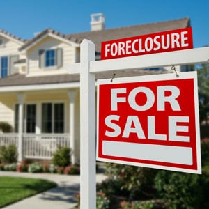 Red 'Foreclosure' and 'For Sale' sign in front of a house symbolizing short sale